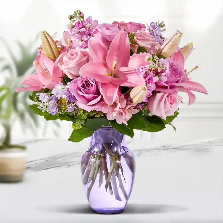 Elegant arrangement of pink lilies and roses in a glass vase.