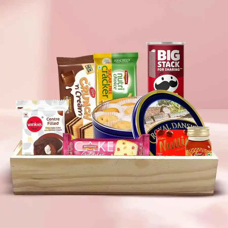 Toothsome Munch Tray filled with Danish Cookies, Britannia Fruit Cake, Winkies Cupcakes, Pringles Chips, Waffy Chocolate Wafers, Dabur Honey, Britannia Cream Crackers, and Cadbury Nutties on a wooden tray.