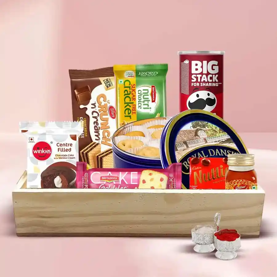 Remarkable Goodies Gift Hamper featuring Danish Cookies, Britannia Fruit Cake, Pringles Chips, Cadbury Nutties, Waffy Chocolate Wafers, Dabur Honey, Cream Crackers, and free Roli, Tika, and Chawal, all beautifully arranged on a wooden tray.