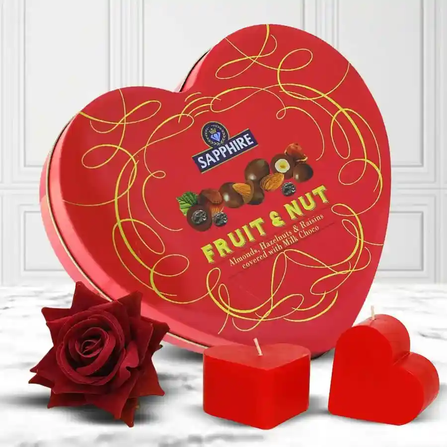 Heart-shaped fruit and nut chocolate box with love candles and a velvet red rose for Valentine's Day gifting