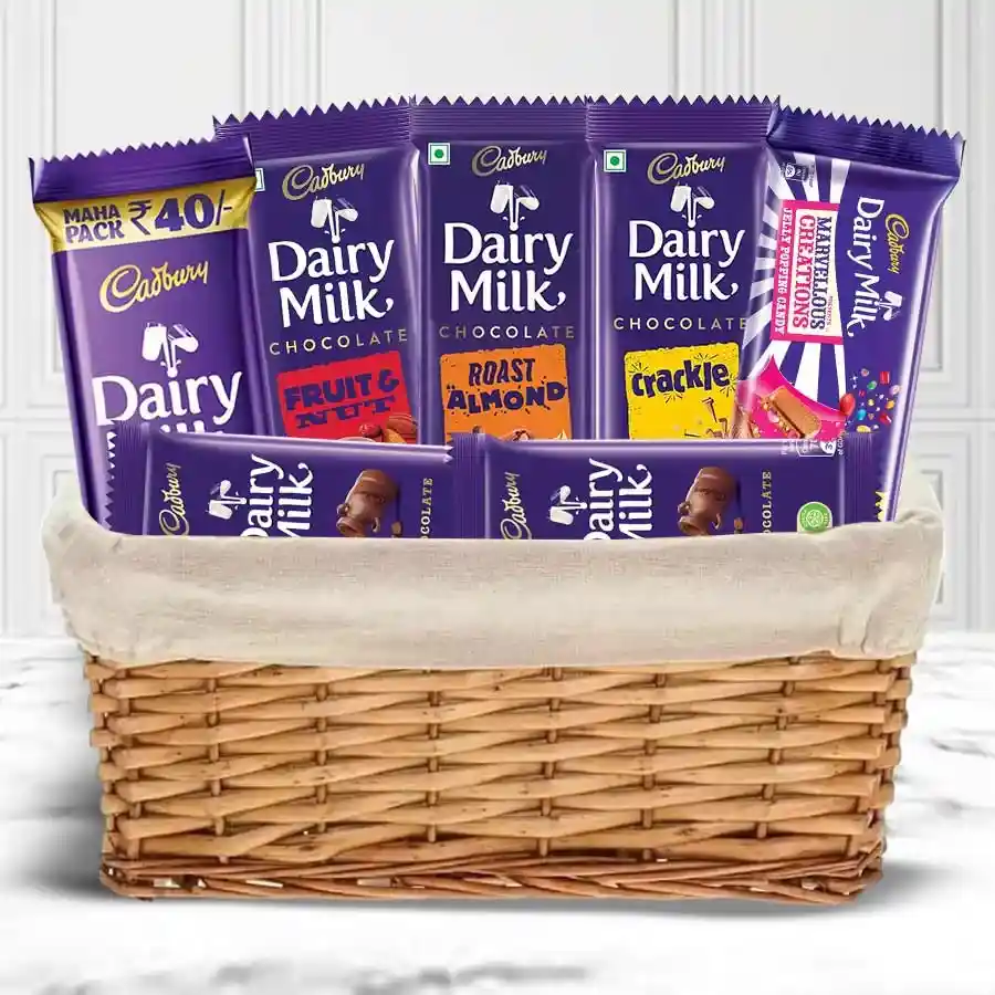 Ambrosial Deepavali Combo featuring assorted Cadbury Dairy Milk chocolates and a decorative candle set in a festive basket