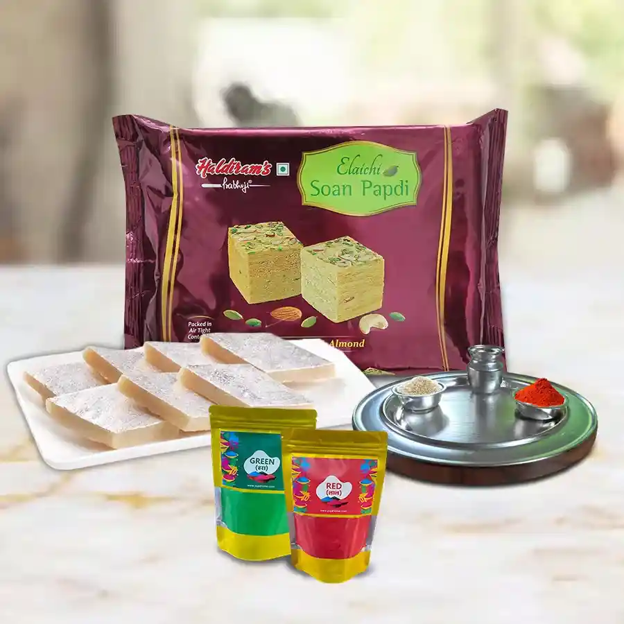 Joyful Celebration Holi Hamper featuring Kaju Katli, Soan Papdi, a silver-plated Puja thali, and herbal gulal