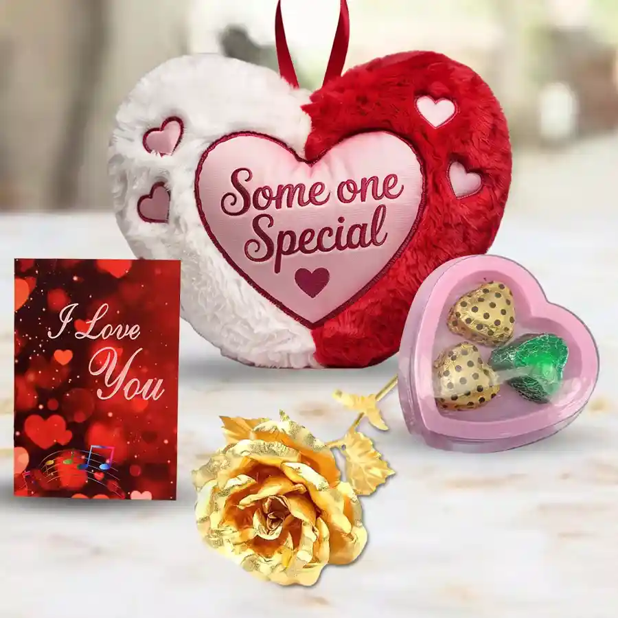 Heart-shaped cushion, handmade chocolates, golden rose, and "I Love You" card arranged in a gift hamper for Valentine's Day.
