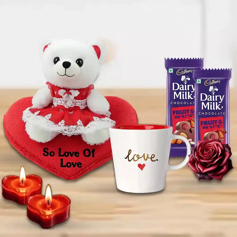 Valentine's Day combo featuring a teddy bear, heart-shaped cushion, Cadbury chocolates, love mug, heart-shaped candles, and a red rose.