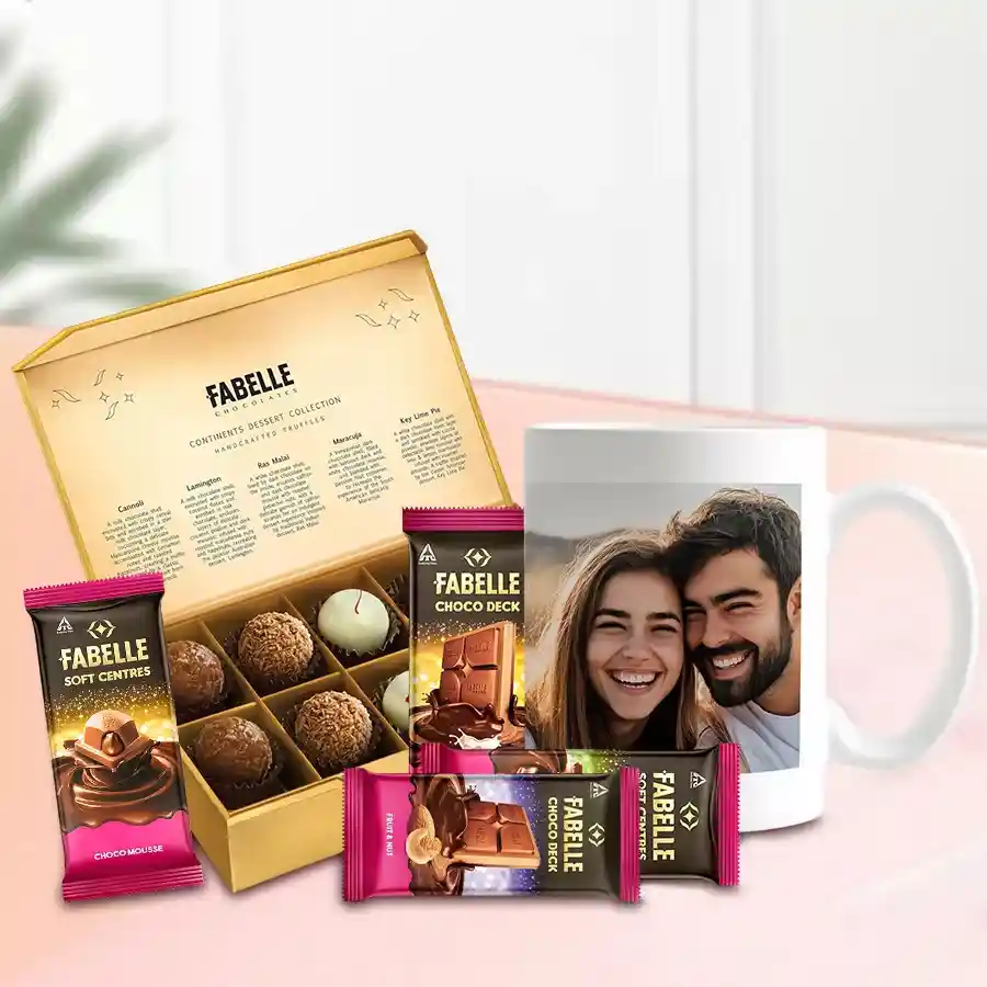 A beautifully arranged gift combo featuring a heart-shaped cushion, a personalized coffee mug, and delicious treats including Fabelle's soft mousse and Choco Deck bars.