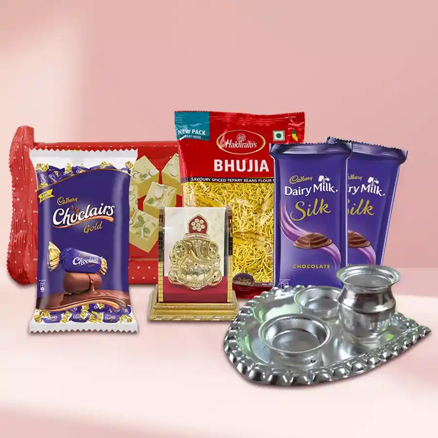 Exclusive Gifts Hamper featuring Haldiram’s Soan Papdi, Bhujia, a silver paan-shaped thali, Vighnesh idol, Cadbury Dairy Milk Silk, and Chocolairs arranged beautifully.