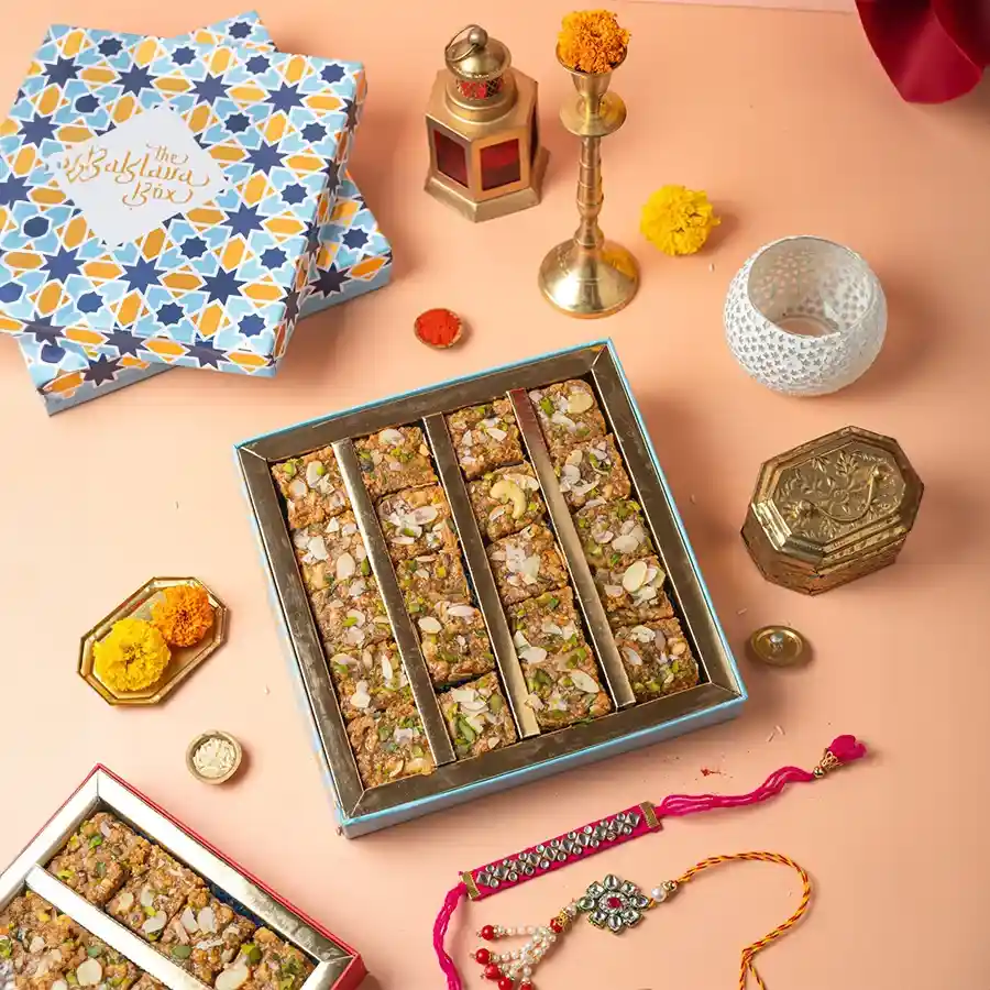A beautifully arranged gift set featuring Malai Doda Burfi and two sets of Rakhi, perfect for celebrating Raksha Bandhan.