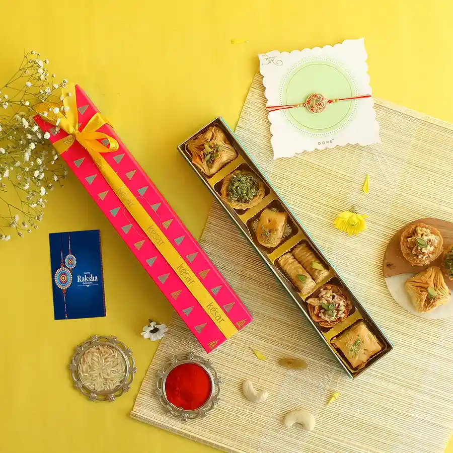 Delightful Rakhi and Baklava Surprise gift box featuring a Red Flower Rakhi, assorted baklavas, Roli Chawal, and a greetings card.