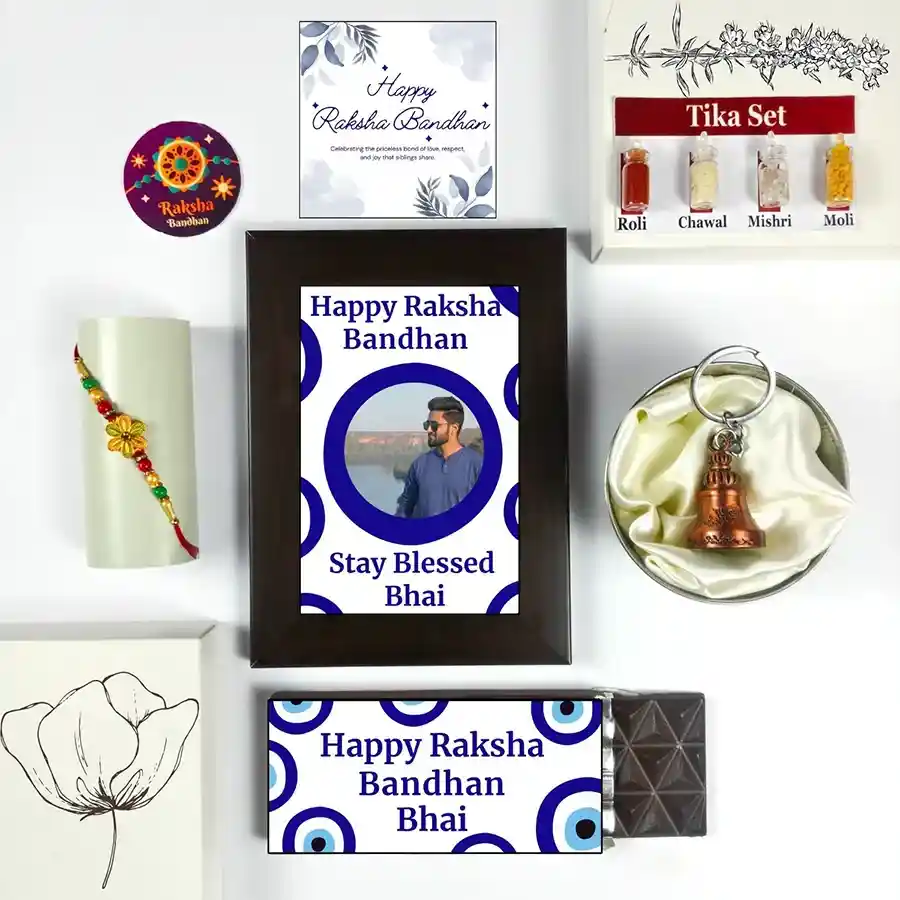 Special Raksha Bandhan Treat Hamper featuring Evil Eye Raksha Bandhan, chocolate, photo frame, greeting card, guardian bell, Rakhi, and Tika set.