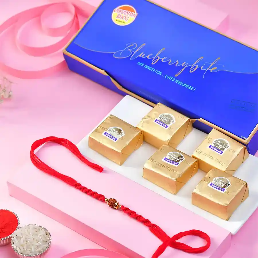 A Rakhi & Blueberry Bites Combo featuring a Classic Rudraksh Rakhi, delicious Blueberry bites, and a traditional Roli Chawal Card, ideal for festive gifting.
