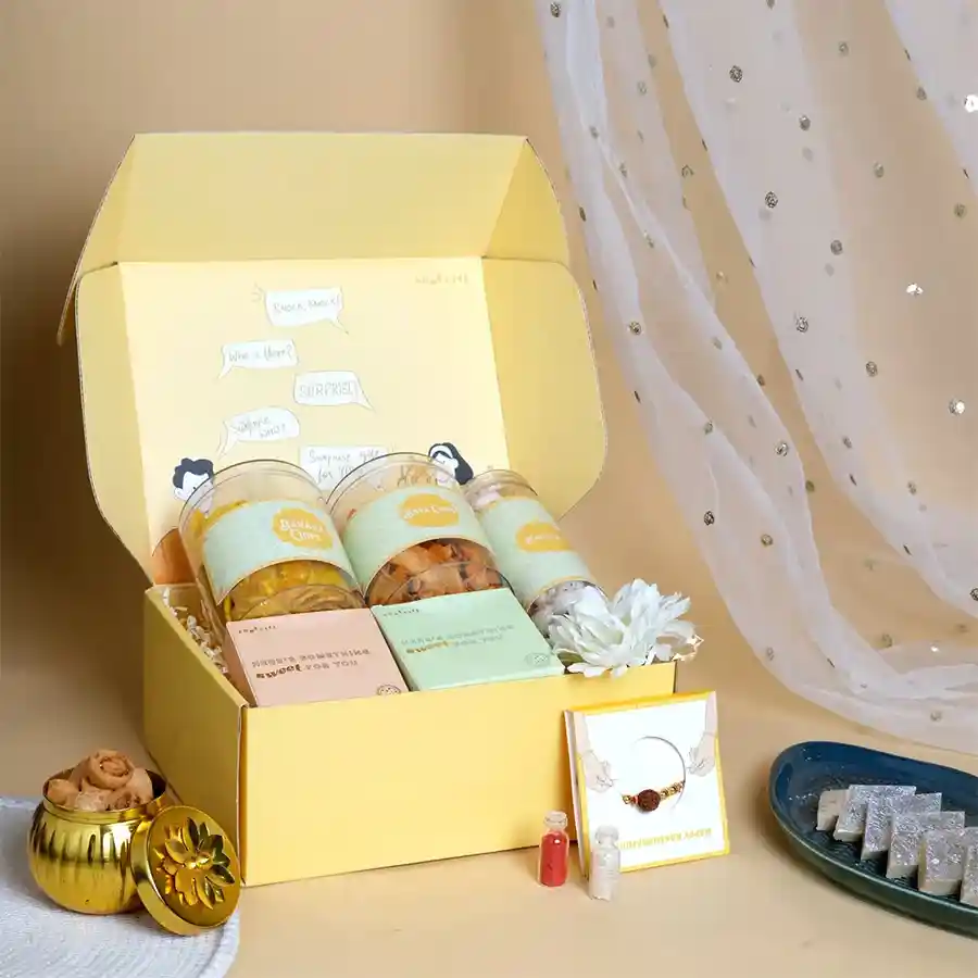 Festive Rakhi and Treats Surprise Pack with Rudraksha Rakhi, snacks, and cookies in a yellow box.