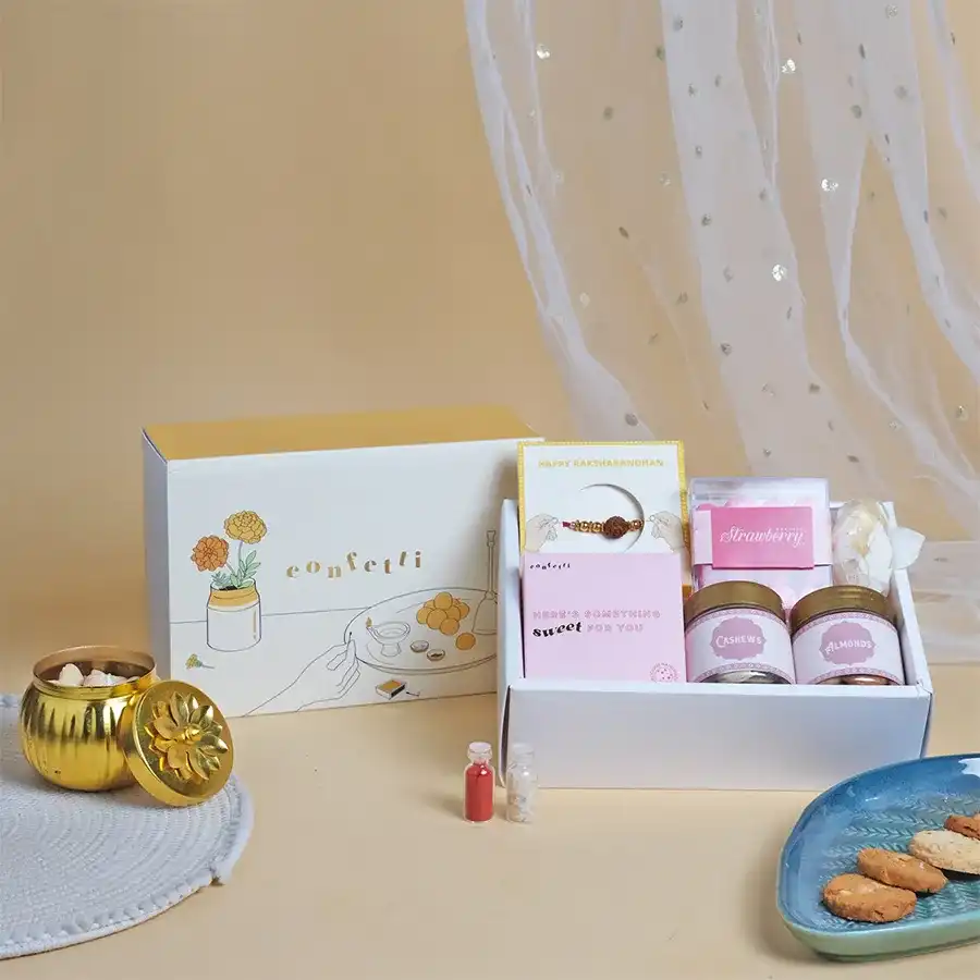 Festive Harmony Rakhi Treats Box featuring Rudraksha Rakhi, cashews, almonds, handmade cookies, and strawberry dragees in a yellow slider box.