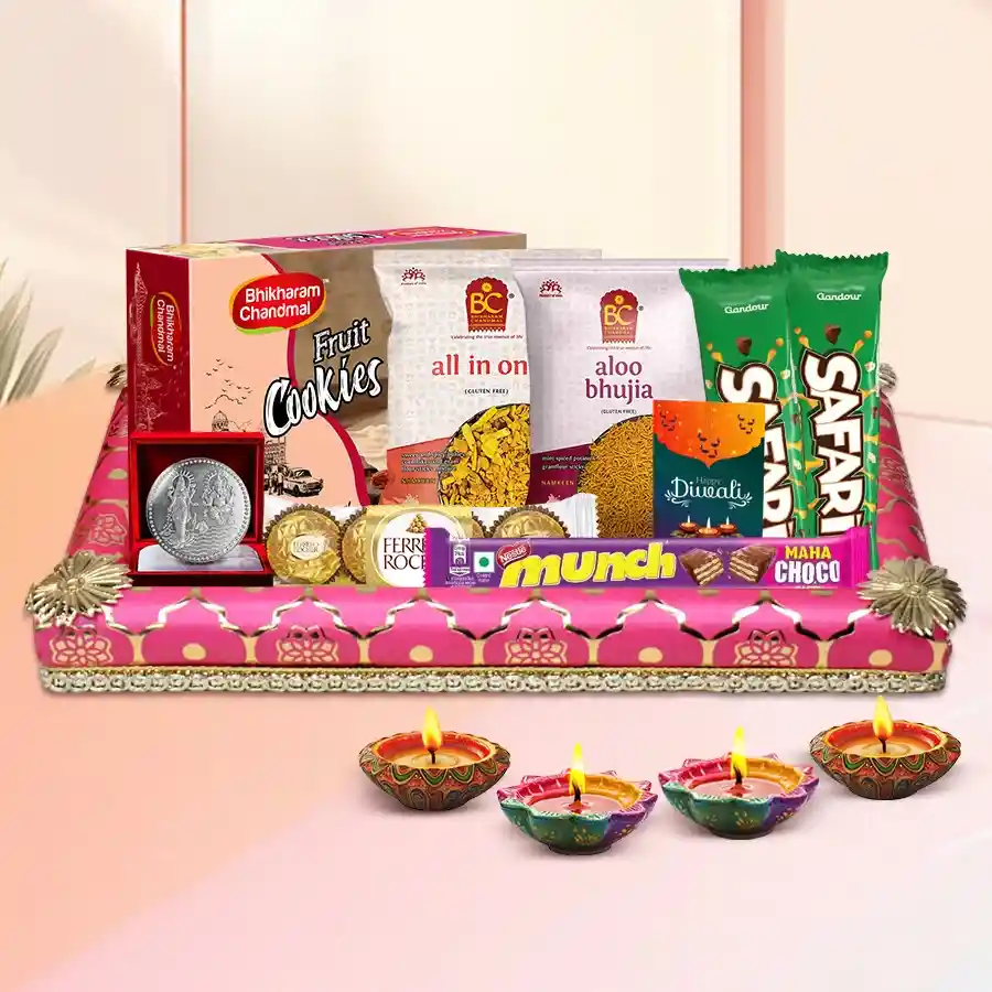 Diwali gift hamper featuring chocolates, snacks, decorative diyas, a silver-plated coin, and a greetings card.