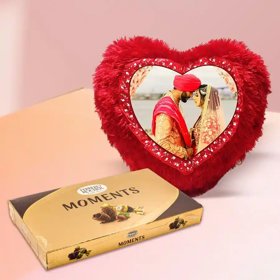 Personalized heart-shaped red cushion alongside a box of 16 Ferrero Rocher chocolates for Karwa Chauth celebration.