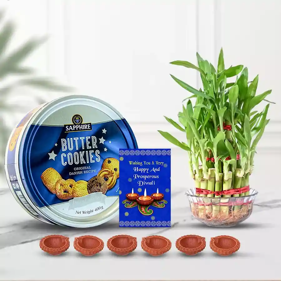 Diwali gift hamper featuring Royal Dansk Cookies, a two-tier Lucky Bamboo plant, six decorated mud diyas, a greeting card, and an additional diya