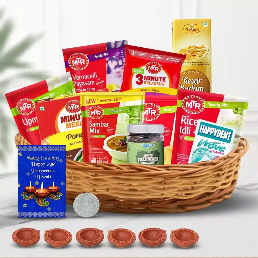 Delicious South Indian breakfast Diwali hamper featuring MTR mixes, sweet treats, mouth fresheners, designer mud diya set, greeting card, silver-plated Ganesh Lakshmi coin, and stylish cane basket.