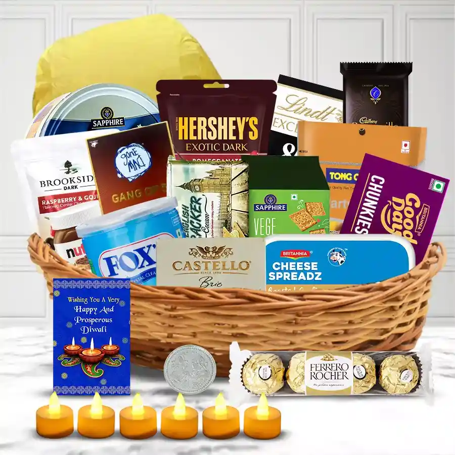 Diwali gift basket featuring cookies, chocolates, cheese spread, crackers, dried fruits, LED candles, a flying lantern, a silver-plated coin, and a greeting card, all elegantly arranged in a cane basket.