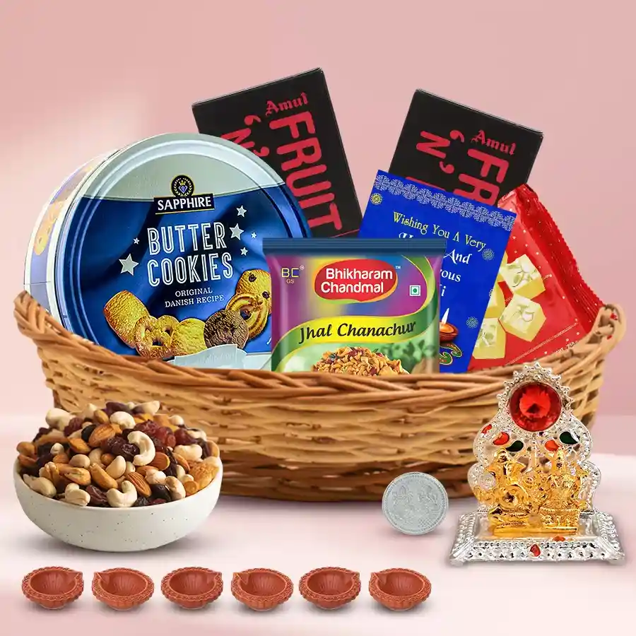 Exquisite Assortments Gift Hamper for Diwali featuring a cane basket filled with Sapphire Butter Cookies, premium dry fruits, Bhikharam Chanachur, Haldirams Soan Papdi, Amul Fruit n Nut Chocolates, a decorative Ganesh Laxmi Mandap, six mud diyas, a silver-plated Ganesh Laxmi coin, and a Diwali card.