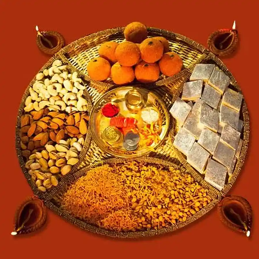 Heavenly Diwali Sweets and Dry Fruits Pooja Thali Combo featuring Kaju Katli, Boondi Ladoo, premium dry fruits, Bhikharam Mixture, decorative diyas, and Pooja Samagri in a stylish cane basket.