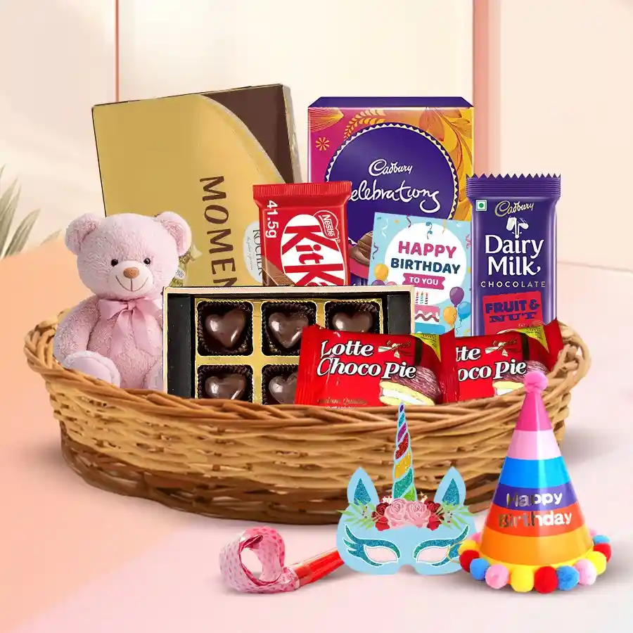 Gift hamper featuring premium chocolates, a teddy bear, and party accessories arranged in a charming cane basket.