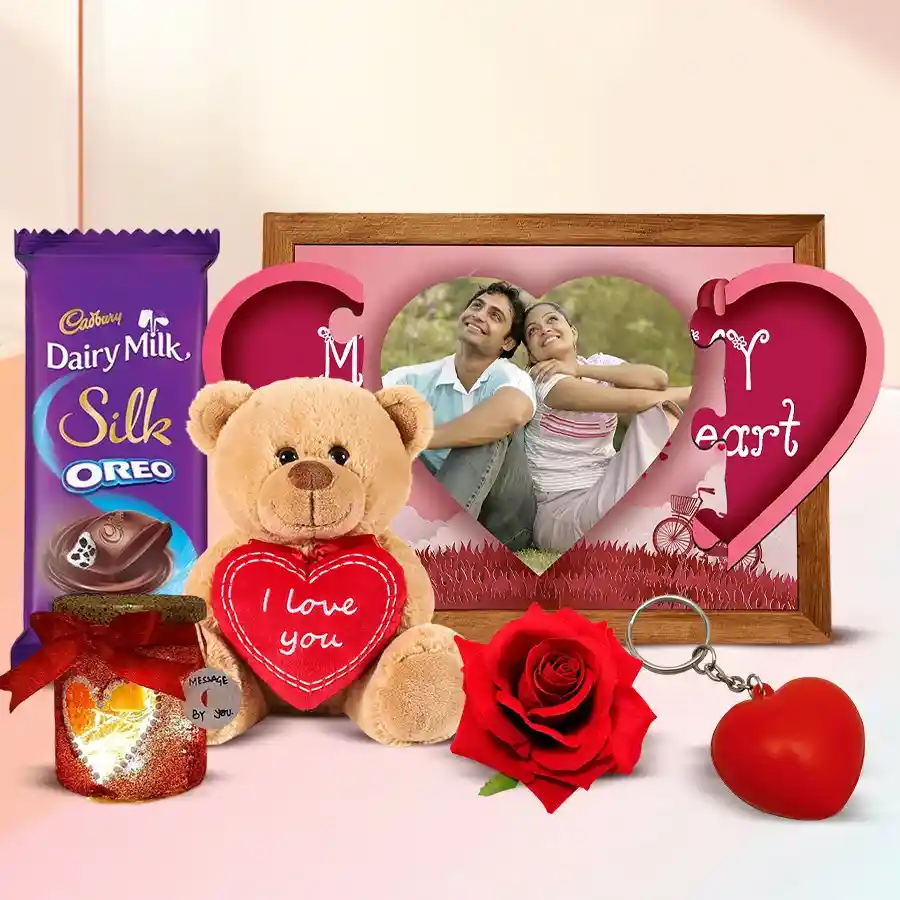 Valentine's Day gift set featuring a personalized photo magnetic heart, Cadbury Dairy Milk Red Velvet chocolates, a handmade heart LED lamp, a velvet rose, a heart-shaped key ring, and a "I Love You" teddy bear.