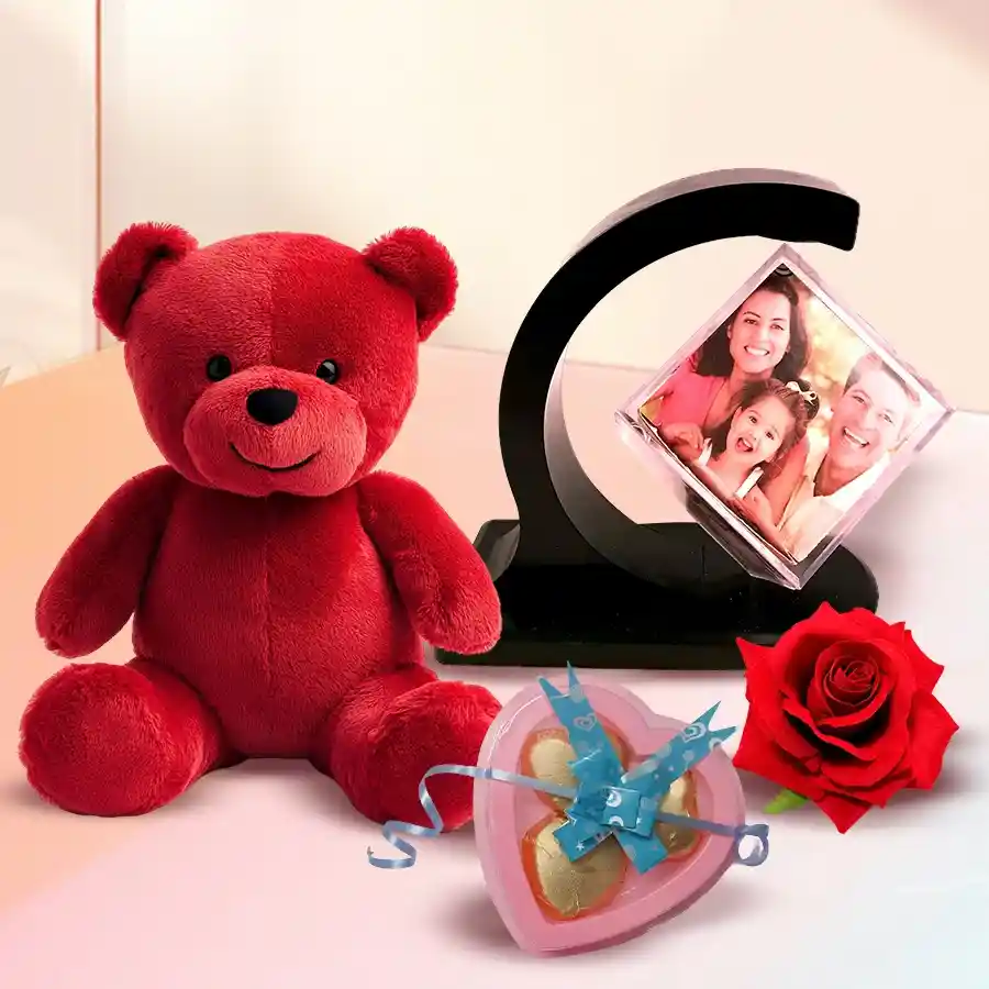 Personalized photo gift combo for Valentine's Day featuring a custom photo magnetic revolving stand, heart-shaped chocolates, a red teddy bear, and a red velvet rose.