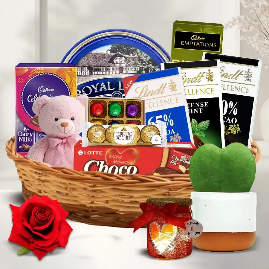 Enticing hamper filled with chocolates, a teddy bear, LED heart lamp, red velvet rose, and heart-shaped plant
