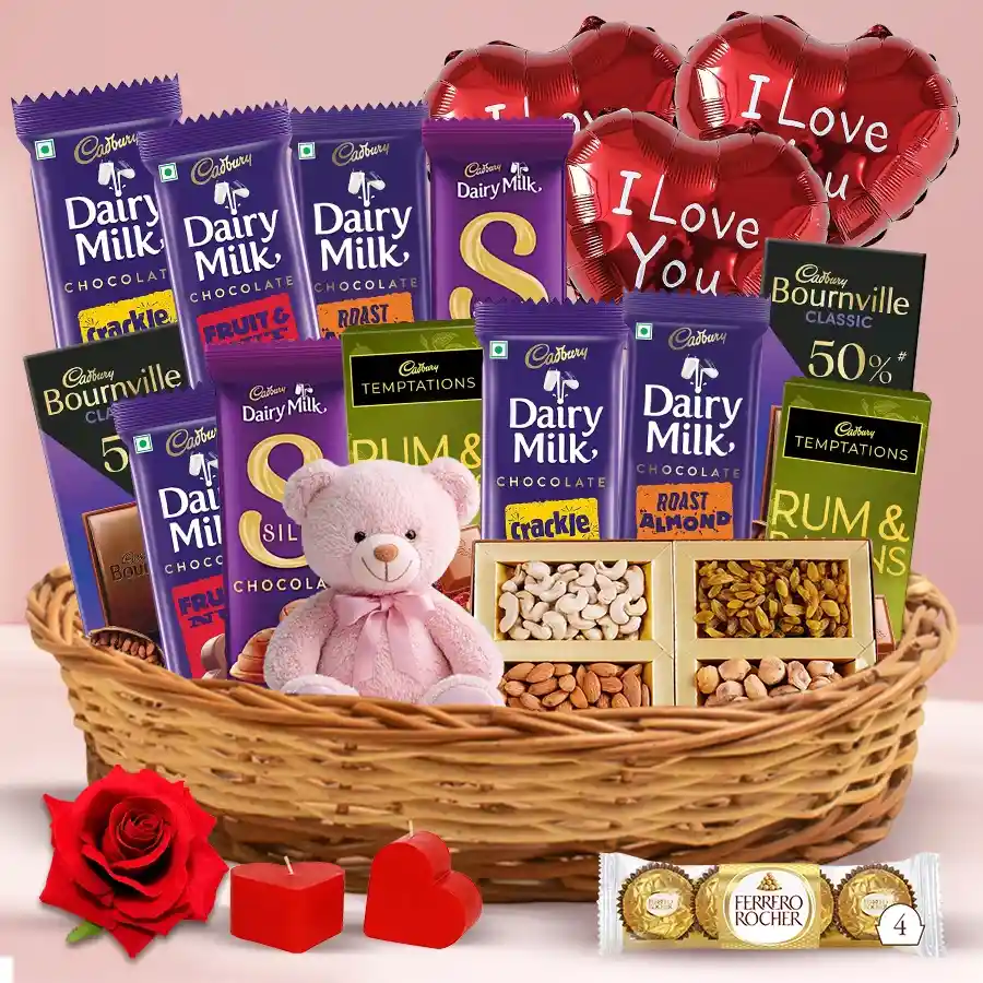 Extravagant chocolate hamper with assorted chocolates, dry fruits, heart-shaped candles, a red velvet rose, a teddy bear, and "I Love You" balloons for Valentine's Day.