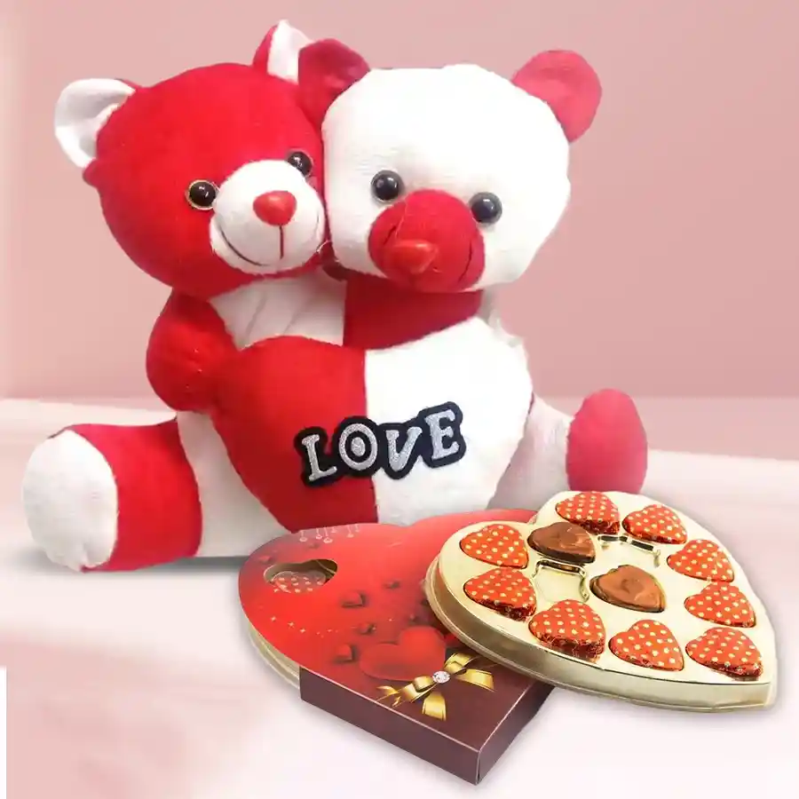 Teddy bear with heart, heart-shaped chocolates, and red velvet roses arranged as a Valentine's Day gift