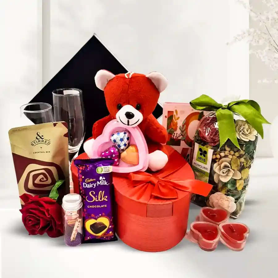 Lovely Aroma of Love Gift Hamper featuring potpourri, Cadbury Dairy Milk Silk, heart-shaped chocolates, wine glasses, teddy bear, scented candles, and a message jar.