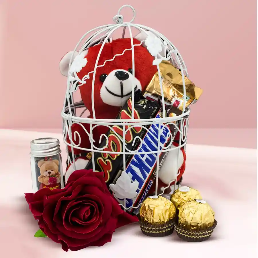 Fabulous Love Teddy with chocolates in a decorative cage, featuring a 6-inch teddy bear, Ferrero Rocher chocolates, Snickers, Mars, Twix bars, a Love Message Jar, and a red velvet rose.