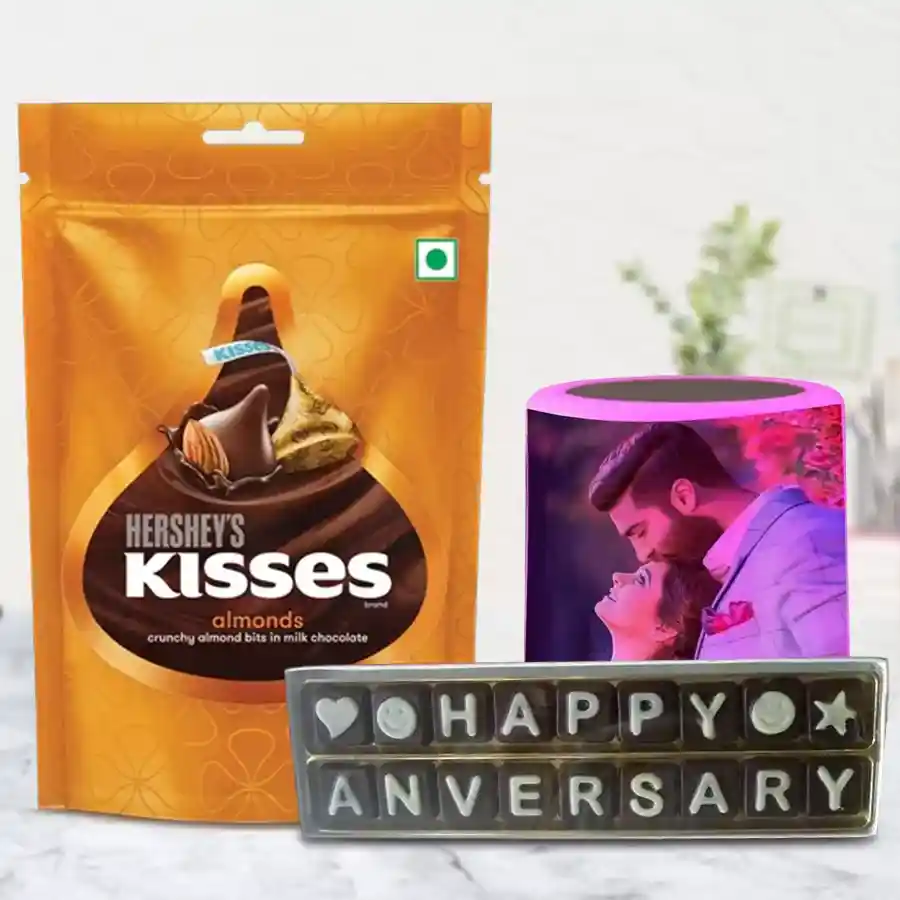 Personalized music speaker with a photo, surrounded by Hershey's Kisses Almond chocolates and handmade chocolates with a "Happy Anniversary" message