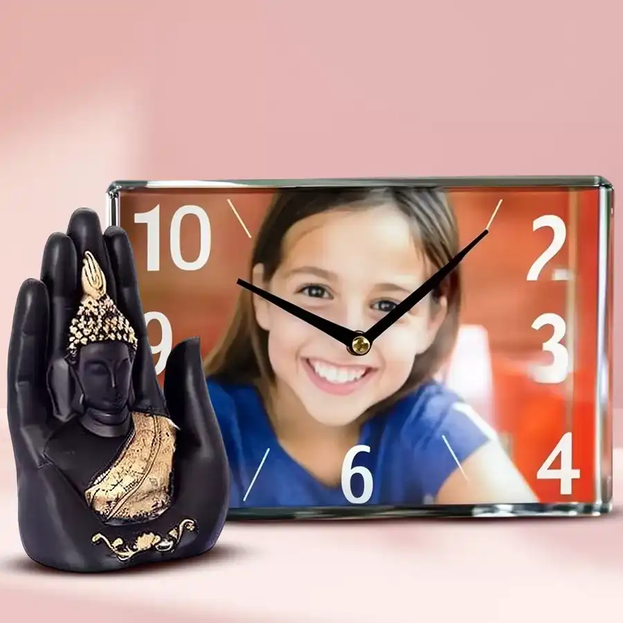 Personalized photo glass table clock next to a Buddha on palm statue on a wooden surface