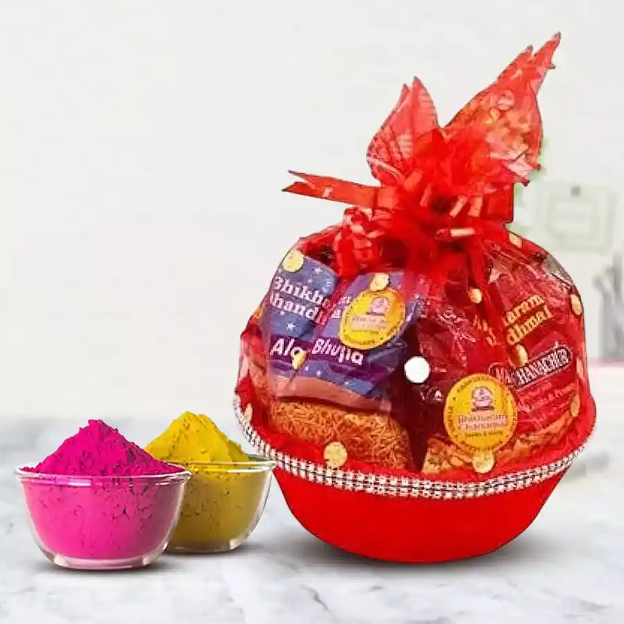 Mesmerizing Munches Gift Basket for Holi featuring namkeen packets, Soan Papdi, Baked Kaju Pista Bites, Cadbury treats, and herbal gulal arranged in a charming basket.
