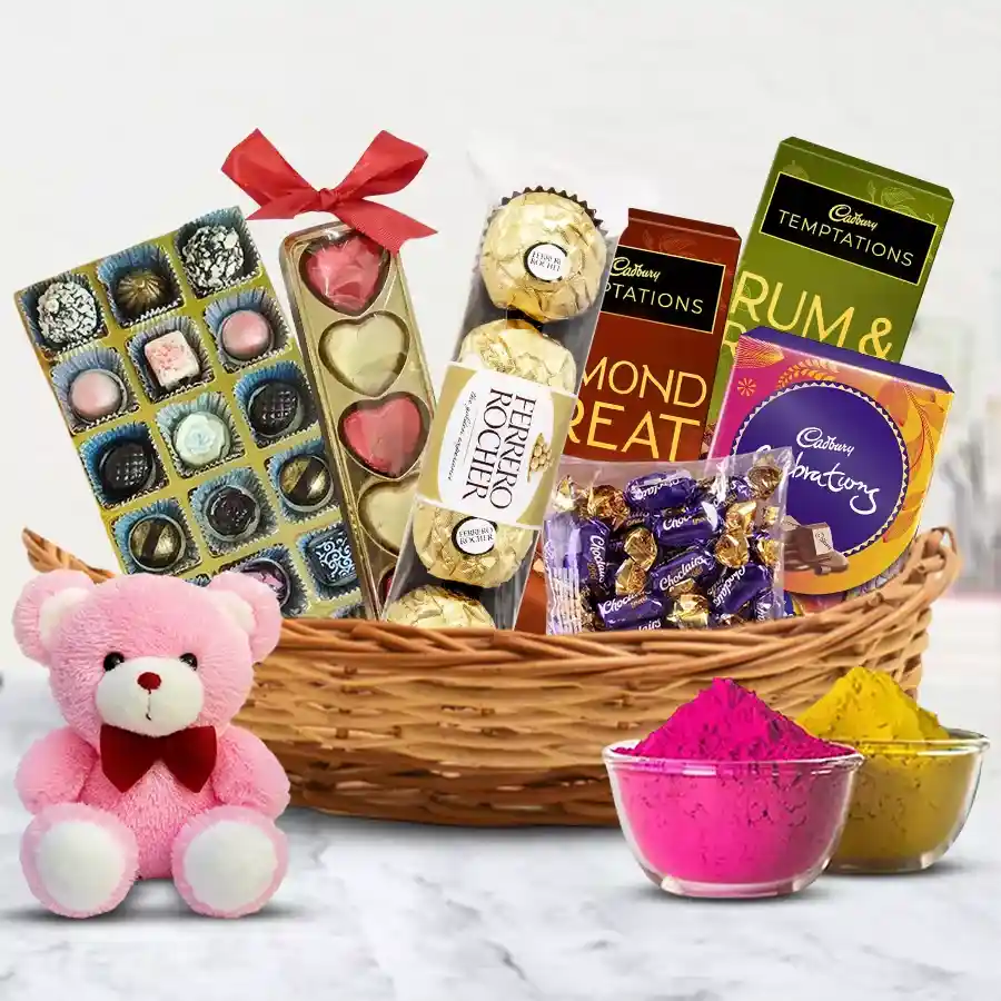 Ambrosial Chocos Gift Basket for Holi featuring homemade and premium chocolates, heart-shaped treats, Ferrero Rocher, Cadbury chocolates, a 6-inch teddy, and multicolor herbal gulal in a charming cane basket
