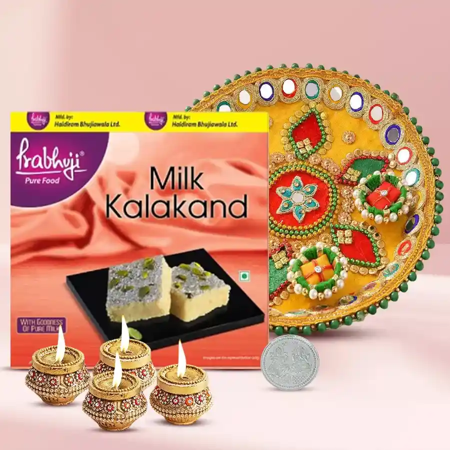 Blissful selection of Haldiram sweets, terracotta diyas, stylish steel thali, and silver-plated Laxmi Ganesh coin arranged for Diwali celebration.