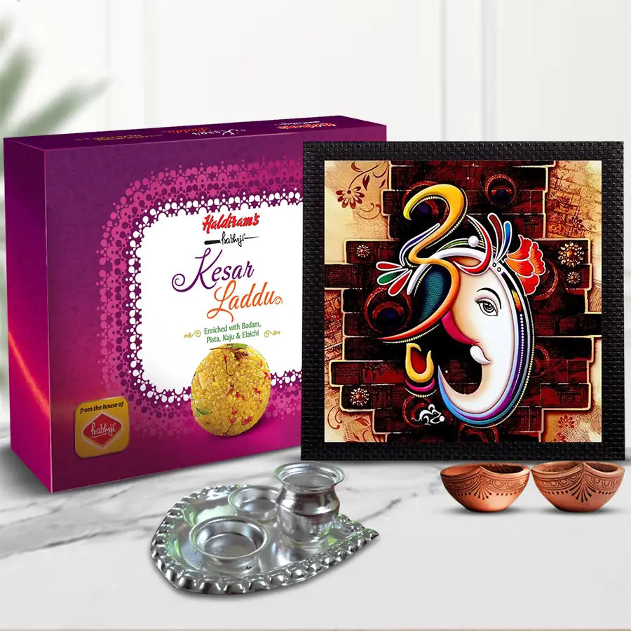 Paan shape pooja thali set with Lord Ganesha UV frame painting, Haldiram Kesar Laddu, silver-plated thali, and terracotta diyas