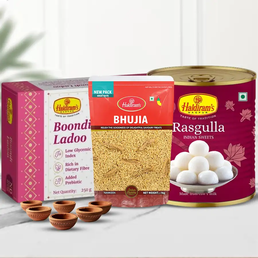 Joyful Diwali gift bundle featuring Haldiram sweets and snacks including Rasgullas, Boondi Ladoos, and Bhujiya, along with decorative Kuber Mud Diyas.