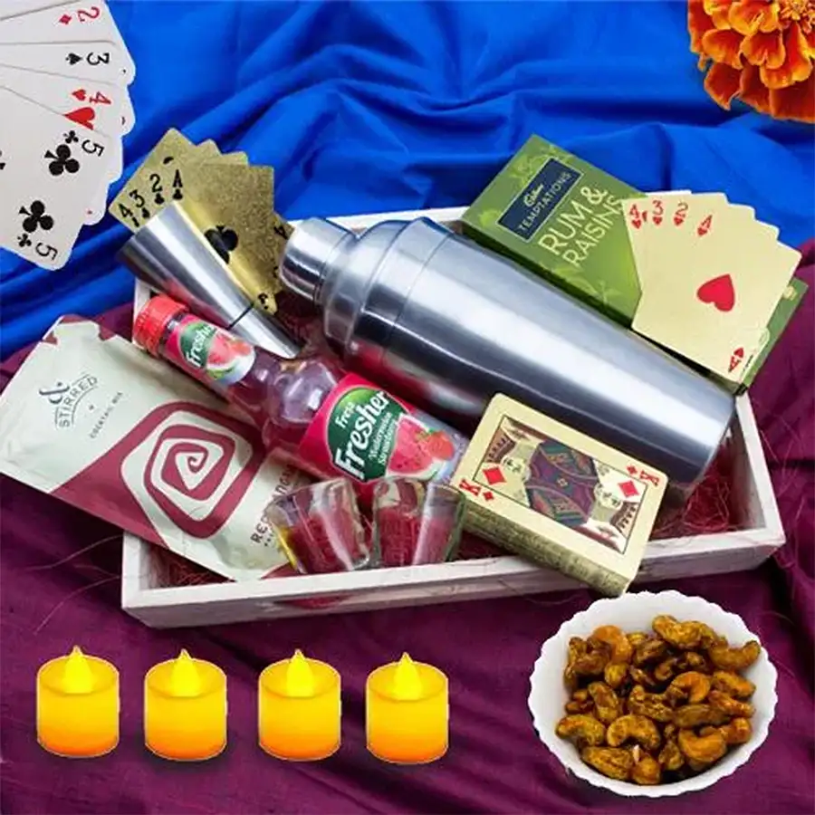 Soothing Diwali Night Combo featuring shot glasses, cocktail shaker, Red Sangria mix, fruit wine, Cadbury Rum & Raisins, masala kaju, gold-plated playing cards, LED tealight candles, arranged in a wooden tray.