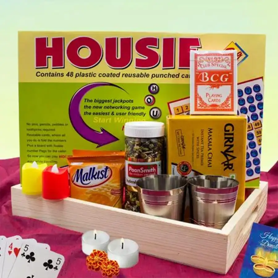 Special Masala Chai and Family Game Combo for Diwali celebrations, including masala chai premix, stainless steel tea glasses, cheese crackers, Hyderabadi mukhwas, playing cards, LED tealight candles, and a housie board game, arranged creatively in a festive setting.