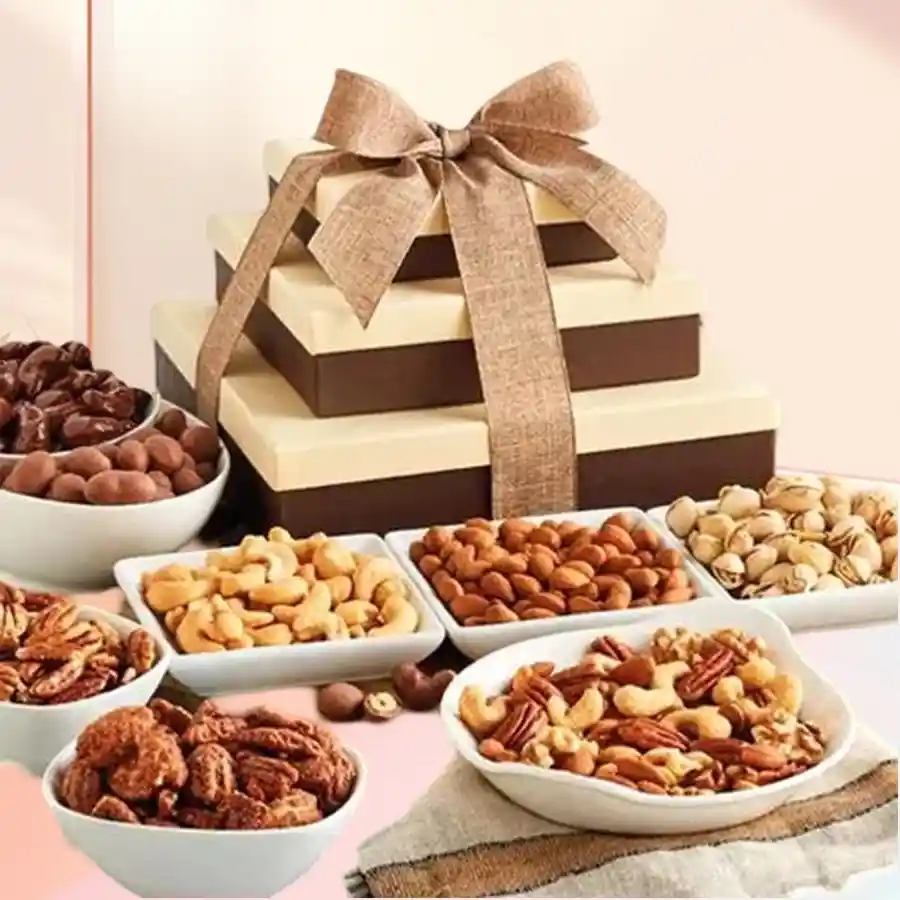 Triple tier gift tower of assorted nuts for Christmas, featuring cashews, almonds, raisins, pistachios, walnuts, apricots, and salted peanuts, elegantly tied with a festive ribbon.