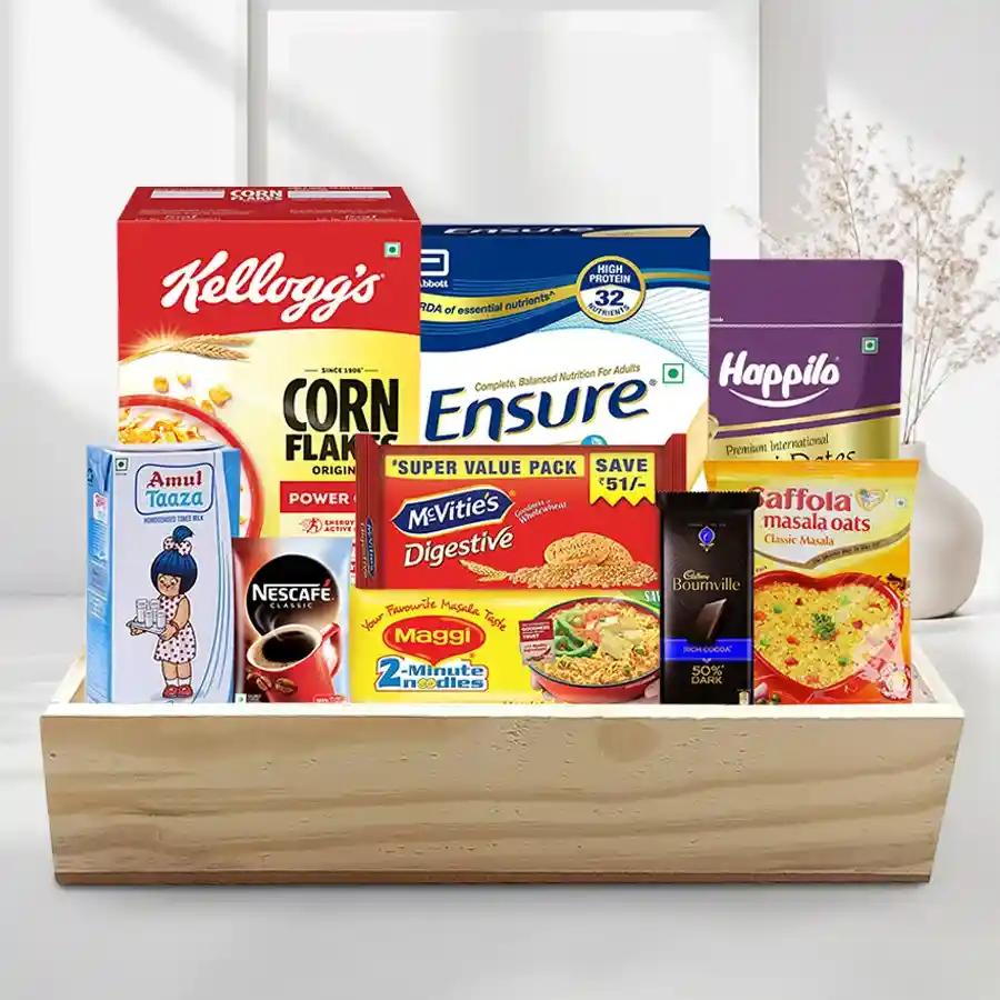 A beautifully arranged breakfast hamper featuring Kellogg's Corn Flakes, Amul Toned Milk, Saffola Masala Oats, Maggi Instant Noodles, Nestle Nescafe, Ensure-Complete Vanilla, McVitie's Digestive Biscuits, Cadbury Bournville chocolate, and Happilo dates presented on a stylish wooden tray.