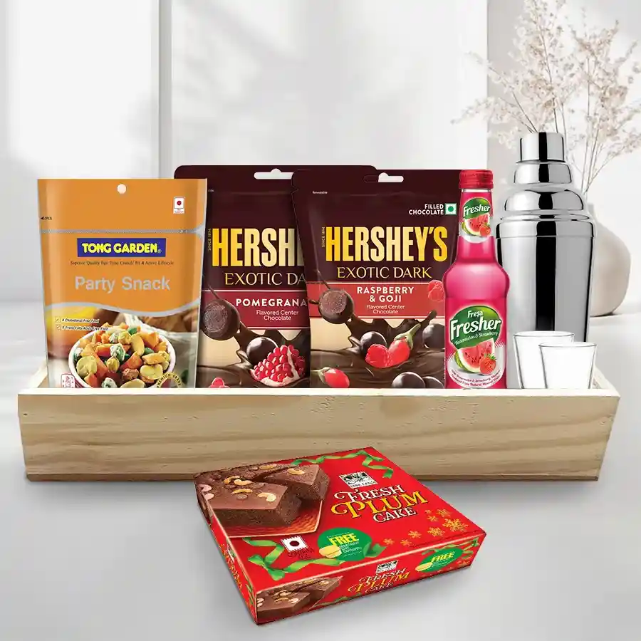 Superb Xmas Treats Snacks Hamper with shot glasses, cocktail shaker, mocktail ingredients, snacks, and plum cake on a wooden tray.