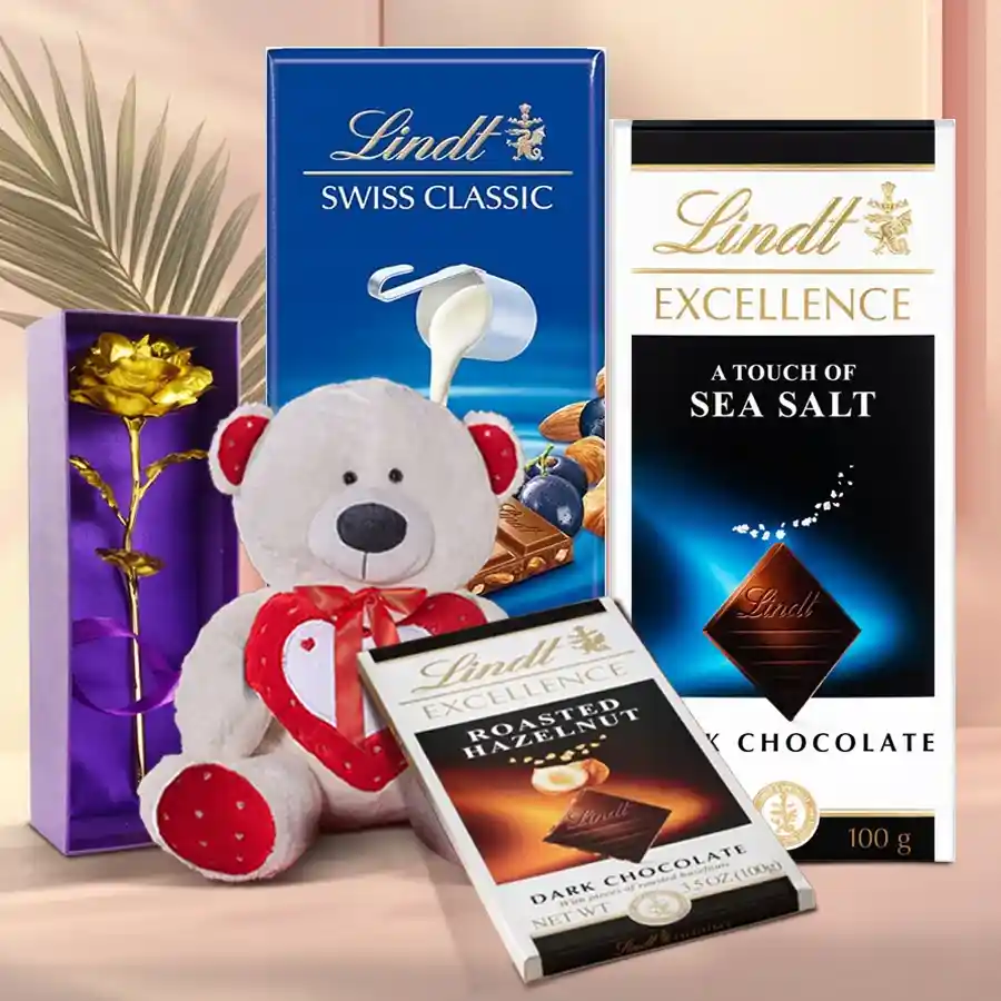 Colorful teddy bear, golden rose, and assorted Lindt chocolates arranged as a Valentine's Day gift