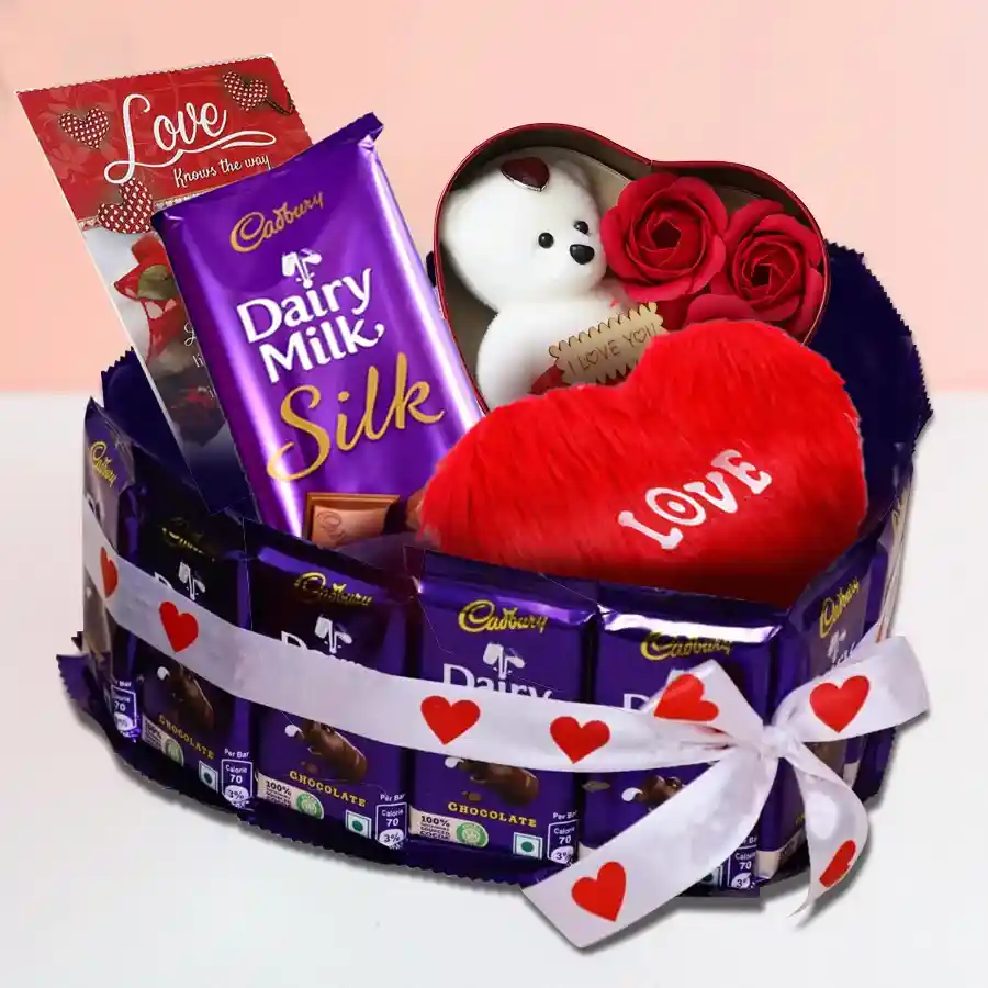 Sweetheart Surprise Hamper featuring Cadbury Dairy Milk chocolates, Dairy Milk Silk bar, heart-shaped box of roses, soft heart-shaped cushion, and a love card