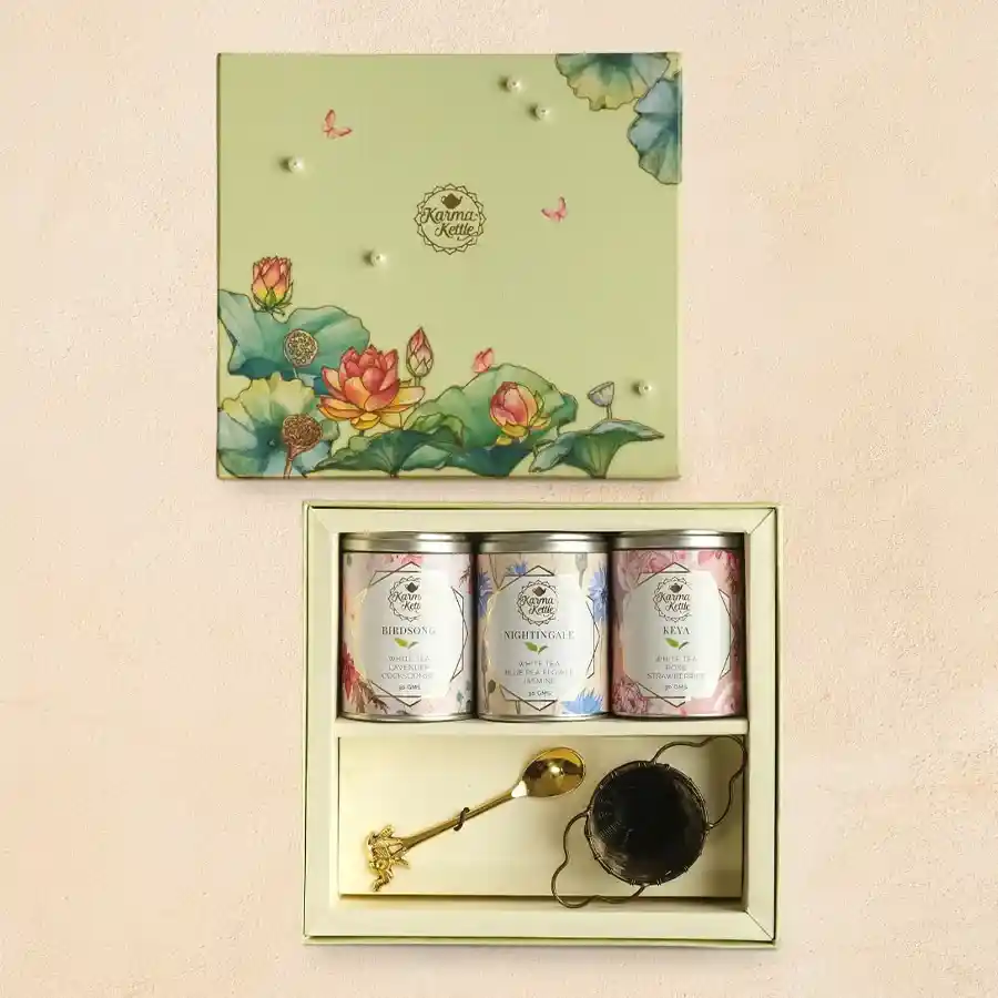 White Tea Trilogy hamper featuring three white tea blends, an antique brass tea strainer, and a brass teaspoon.