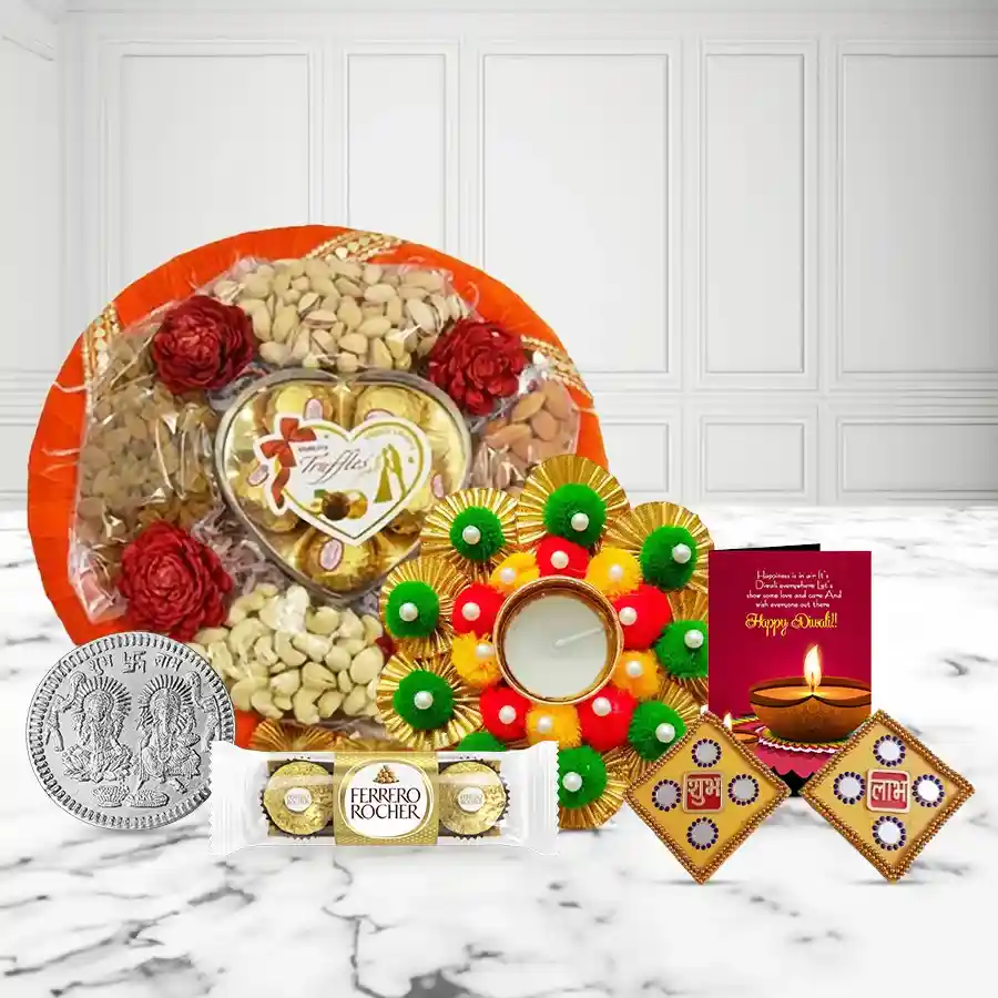 Nutty Delight Tray with Fancy Diya featuring cashews, raisins, almonds, pistachios, Sapphire Hazellfill chocolates, Ferrero Rocher, a decorative diya, Shubh Labh wall stickers, a silver coin, and a Diwali greeting card.