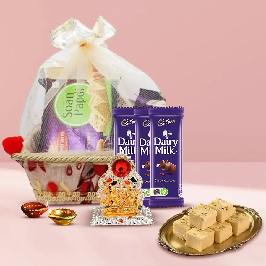 Blissful Sweets Galore Diwali gift hamper featuring Soan Papdi, Cadbury Dairy Milk bars, wax diyas, and a Ganesh Laxmi Mandap in a decorative basket.
