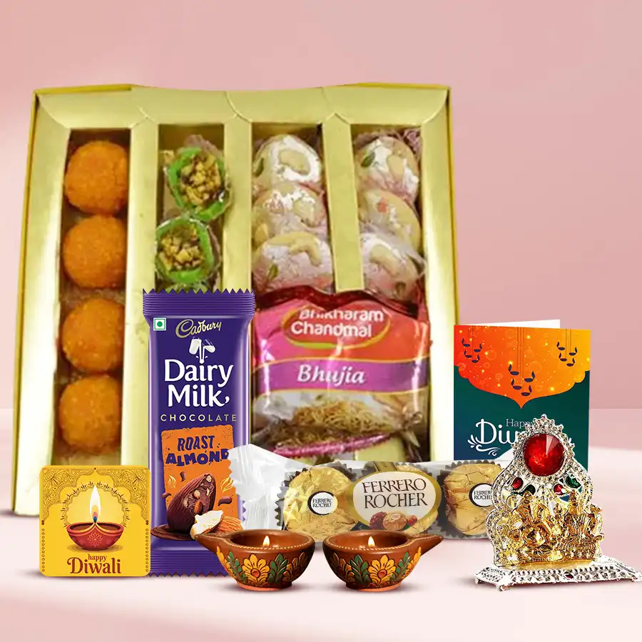 Hamper containing Diwali sweets, snacks, chocolates, diyas, a fridge magnet, a Ganesh-Laxmi mandap, and a Diwali card.