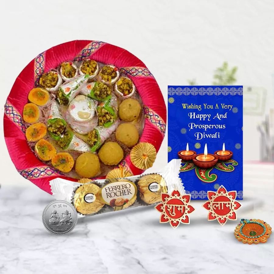 Festive gift hamper featuring traditional sweets, Ferrero Rocher chocolates, a stylish diya, wall stickers, a silver-plated Ganesh Laxmi coin, and a Diwali card.